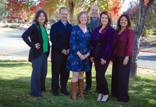 Six of the Foundation members standing under a tree in a group.